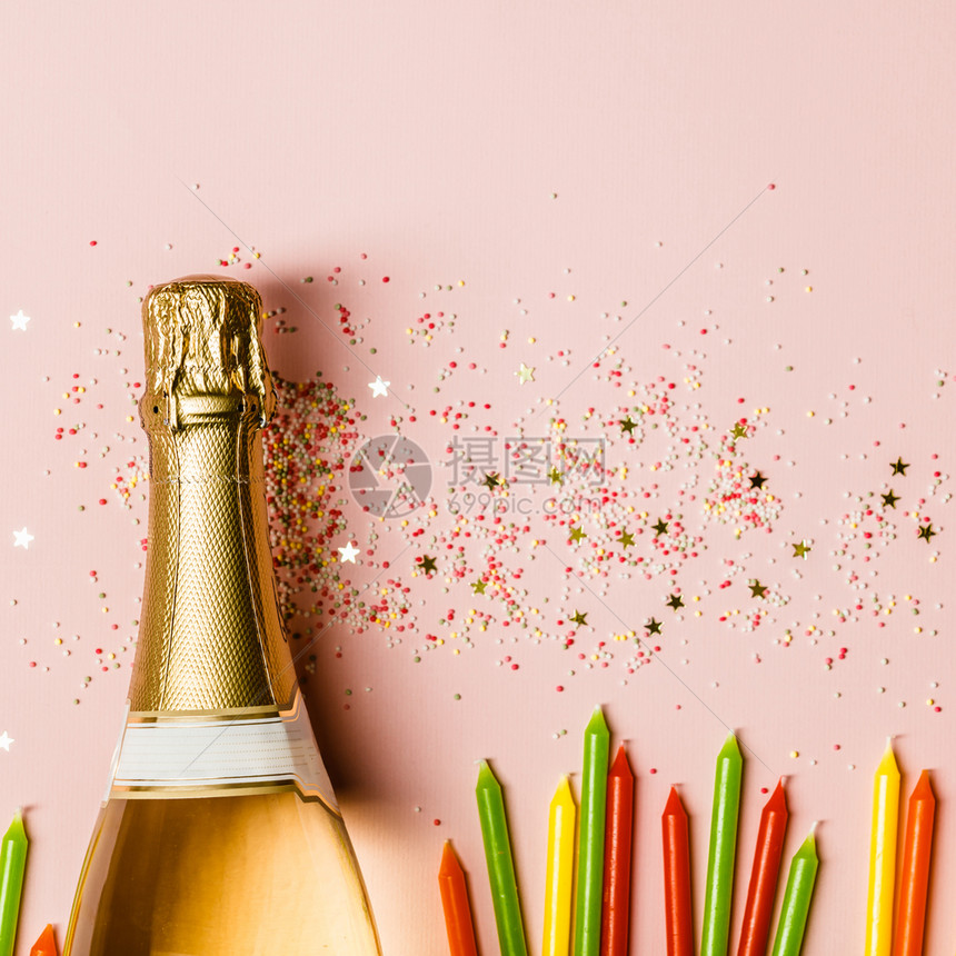 纯净的庆典香槟瓶子加冰淇淋喷洒金星以及粉红色背景的生日蜡烛顶端的景色粉红背的香槟瓶子加粉红色背景的喷洒图片