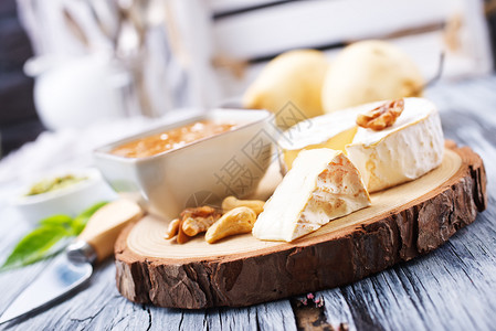 木板上的奶酪坚果蜂蜜和新鲜梨子图片