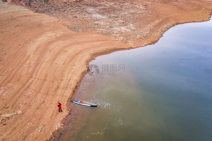 在湖岸边穿干衣的站起式护滑板空中观察典型的冬季风景科罗拉多北丘陵无雪水位低图片