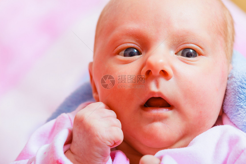 穿着睡衣躺在背面的小新生婴儿面部表情家庭父母童年概念新生儿躺在睡衣和毛巾中图片