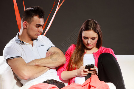 女使用手机发短信和送息男无聊坐在沙发上妻子对新技术上网瘾关系不好女使用手机发短信男无聊背景图片