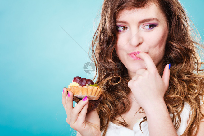 紧贴着笑可爱的卷发女人手拿着水果蛋糕图片