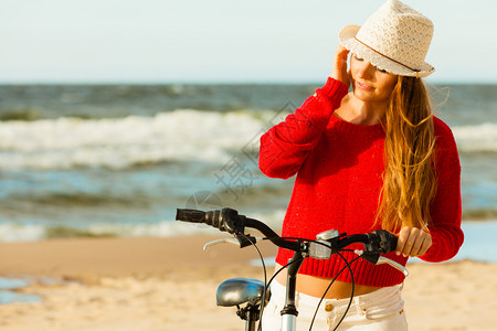 穿着红色毛衣的女子在海边骑自行车图片
