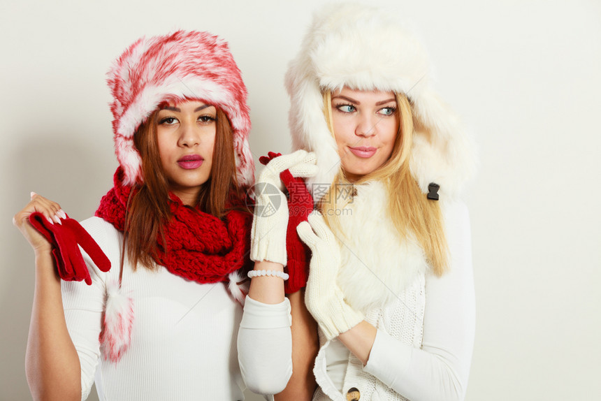 时装冬季饰概念两个金发女孩和黑穿着温暖的红色白服装肖像两个穿着毛帽围巾手套的迷人女两个穿着温暖的冬季服装肖像女孩图片