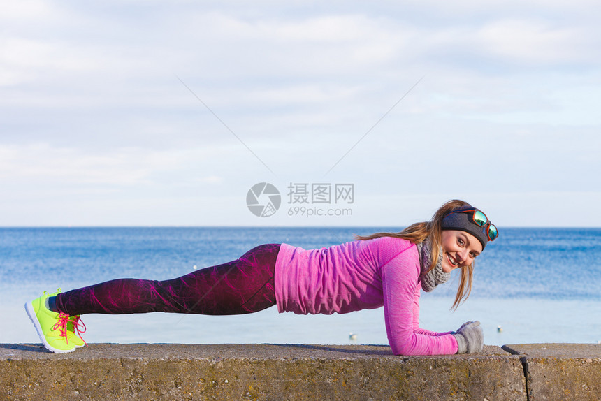 在寒冷的天气下在海边外穿着温暖运动服的女员培训在冬季或秋天的体育和活动图片