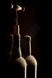 与旧的灰尘葡萄酒瓶和黑底的软木子一起永存背景图片