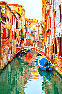 在意大利威尼斯用小型桥和机动艇的狭小运河背景图片