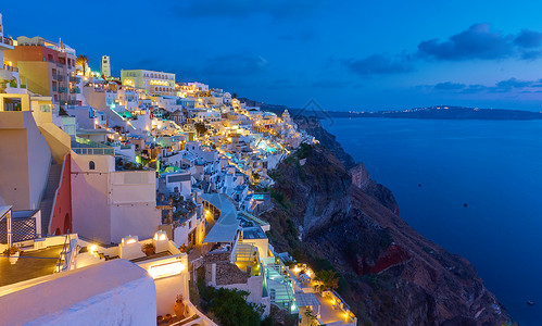 悬崖餐厅在希腊圣托里尼的夜Thira镇在岩石上背景