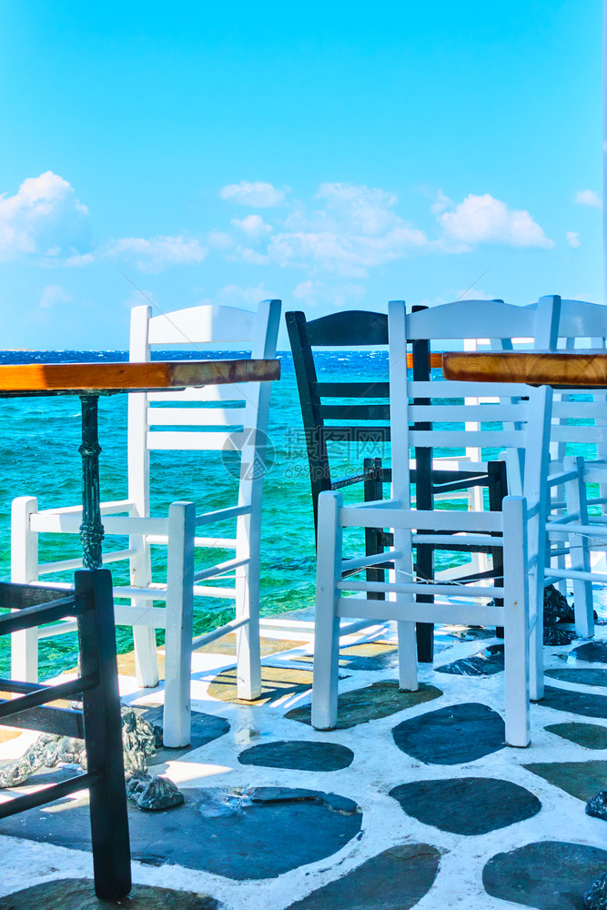 希腊岛海岸边的咖啡桌和椅子图片