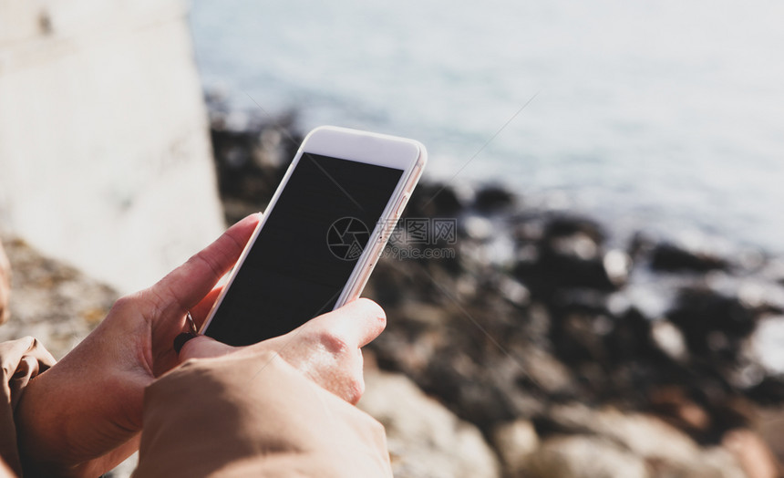 在海滩上使用智能电话的美女图片