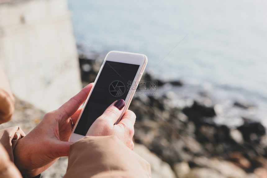 在海滩上使用智能电话的美女图片