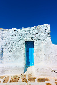 希腊米科诺斯古白漆墙上的狭小蓝色门图片