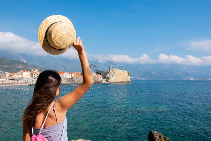一位戴着帽子的年轻美女看着黑山的老城布德瓦夏季度假目的地图片