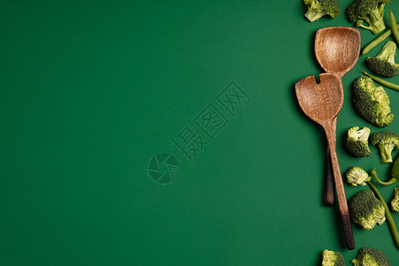 绿色背景的花椰子和汤匙切片季节蔬菜的顶端视图健康饮食的概念图片