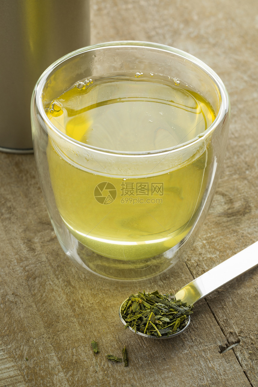 一杯日本绿茶和勺干叶的汤匙图片
