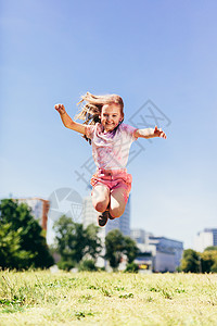 女孩穿着多彩的脏衣服在市公园跳高童年的乐趣在外面玩耍小女孩穿着多彩的脏衣服跳高在市公园背景图片