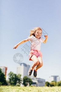快乐的小女孩在草原上跳高夏天在城市童年图片