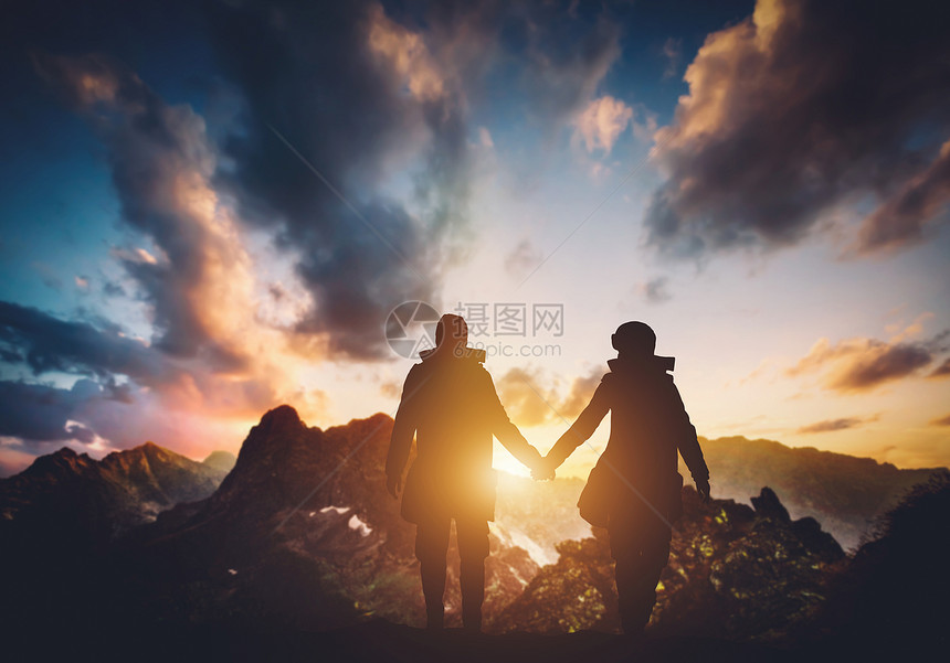 日落时在山上行走的情侣图片