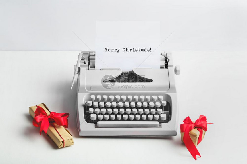 带有MERRYCHISTMAS文本和白色背景礼物的虚拟打字机冬季假日带有MERRYCHISTMAS文本和礼品的打字机图片