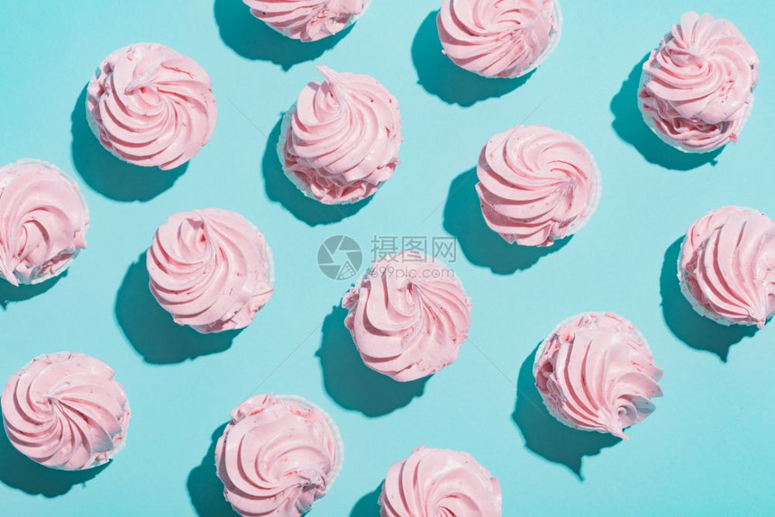 蓝背景的粉红纸杯蛋糕由模式组成甜点平躺粉红背景的纸杯蛋糕图片