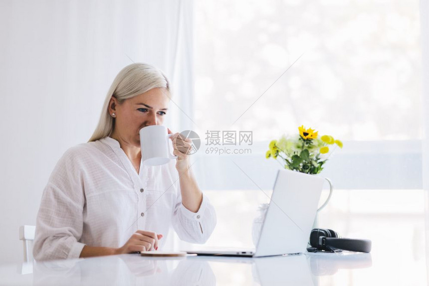 在家用笔记本电脑工作的妇女喝咖啡自由职业商人图片