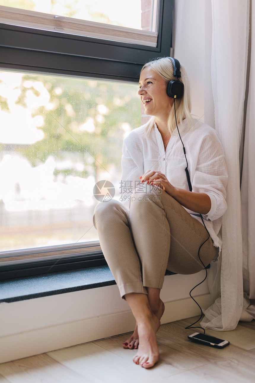 听音乐的开心女人坐在窗边休息时间娱乐图片