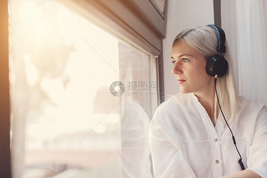仔细思考的听音乐女人透过窗户看音乐闲暇放松怀旧听音乐图片