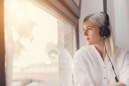 仔细思考的听音乐女人透过窗户看音乐闲暇放松怀旧听音乐图片