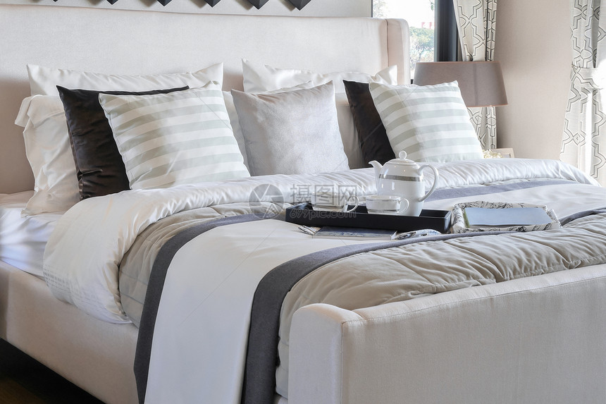 现代卧室床上装饰用书和优雅茶的装饰盘子图片