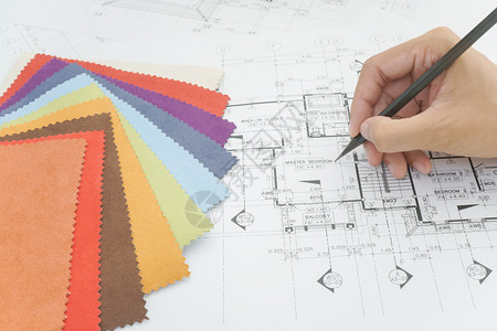 建筑设计师用手在创意桌上抽取现代房子的颜色和材料样本图片