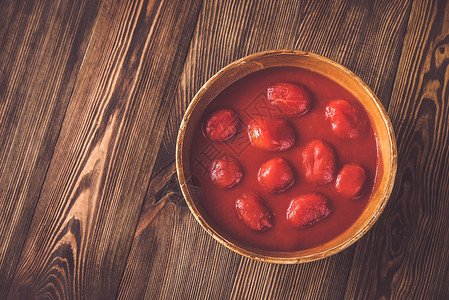 诺丽果木背景上一碗番茄罐头背景
