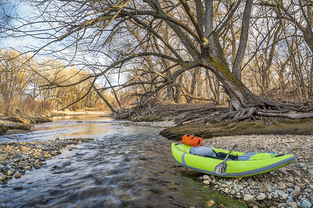 河岸上一条带桨和防水的斗篷白充气皮艇科罗拉多福特柯林斯堡的Poudre河早春风景和低水背景图片