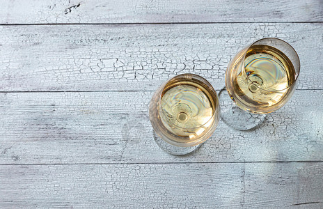 两杯白葡萄酒放在木背景上高清图片