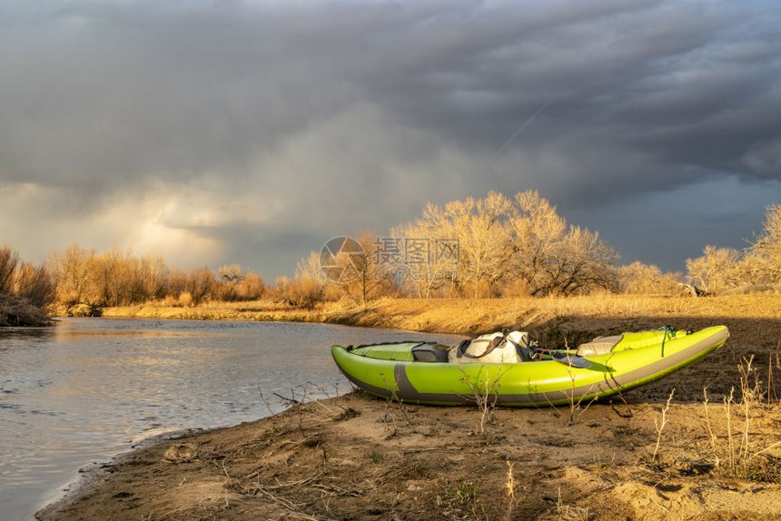 河岸上一条带划桨和防水的斗篷白充气皮艇科罗拉多Platteville附近的StVrain溪初春风景日落时有暴云图片