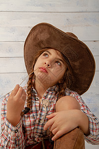 牛仔女郎戴着宽的牛仔帽和穿着传统服装的小女孩摆姿势拍照背景