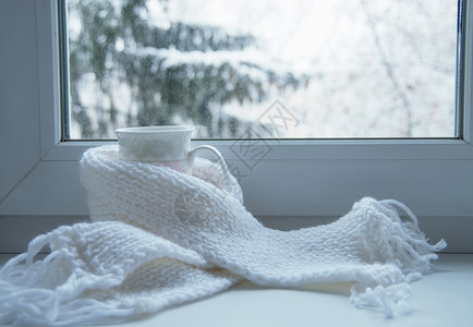 窗台上的热茶和羊毛编织外面的雪景对比图片