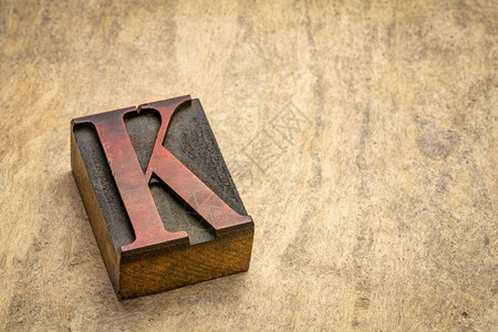 字母KK在旧式印刷纸木型打块中与带有复制空间的纸质树皮相对图片