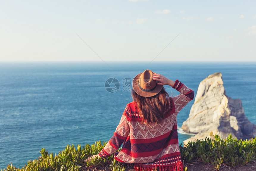 穿着旅行服和帽子坐着看蓝色的海洋和天空旅行概念照片穿旅行服和帽子坐着看蓝色的海洋和天空图片