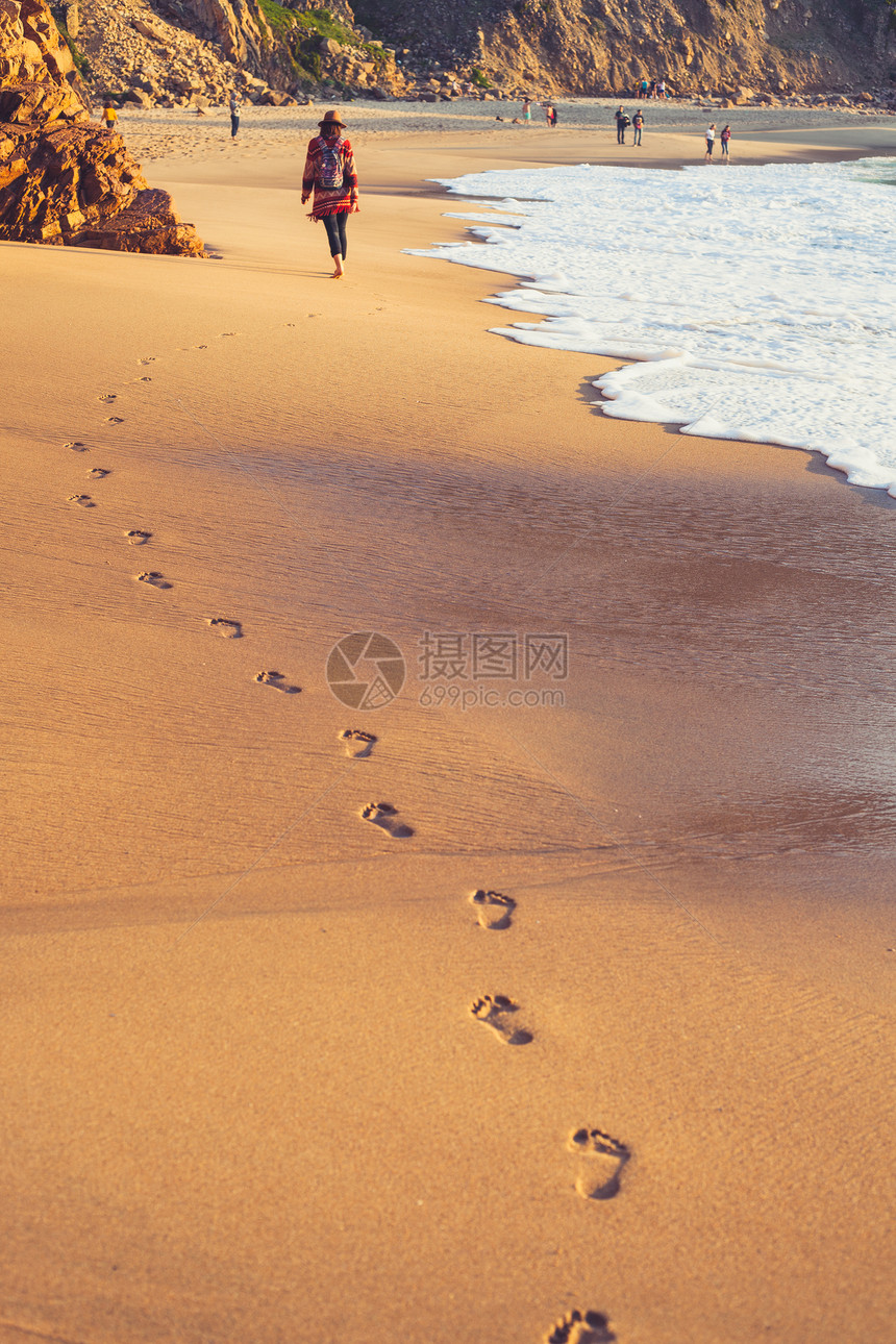 日落时热带海滩的浪和脚印图片