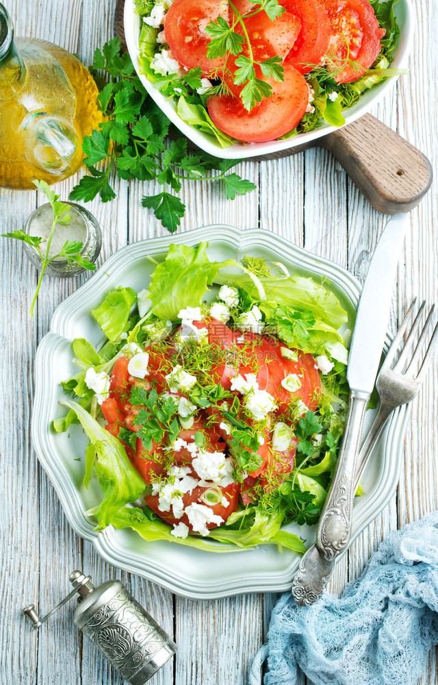蔬菜沙拉加绿色番茄切片和金属盘上的食物图片