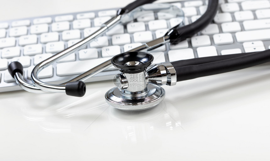 具有传统听诊器和背景计算机键盘的医学保健概念图片