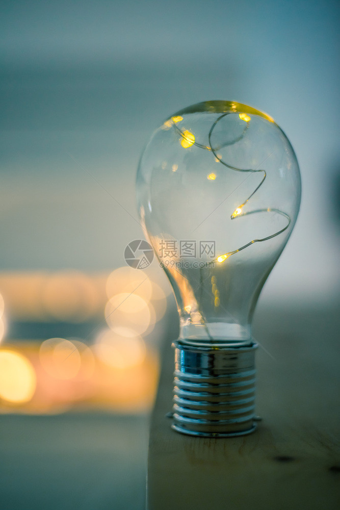 LED灯泡躺在木制桌子上是思想和创新的标志是模糊背景中的亮光图片