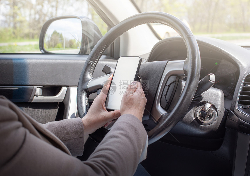 年轻女驾驶员使用触摸屏幕智能手机和GPS在汽车中导航图片