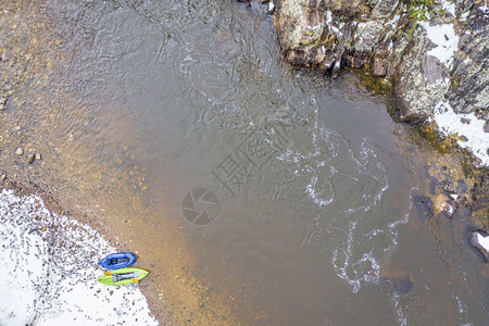 春季暴雪时科罗拉多Poudre河岩石海岸的可充气白水皮艇和背包图片