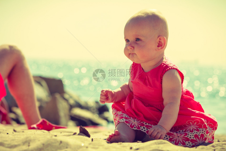 小孩坐在海边滩上玩图片