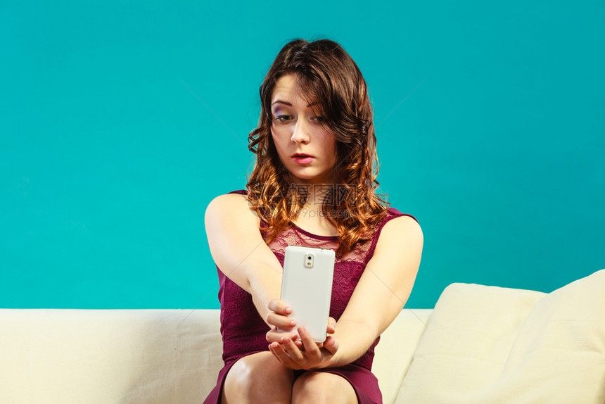 技术互联网和幸福概念年轻时尚女孩在家里沙发上用智能手机相拍自图片