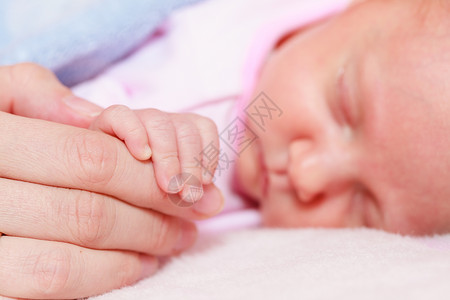 童年无罪概念小可爱的新生儿睡在床上亲着母的手婴儿睡在毯子中图片