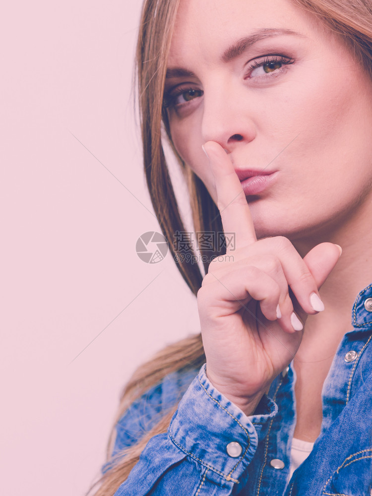 时装人们牛仔裤概念女士用手指对着嘴女孩穿牛仔衬衫女士用手指对嘴图片