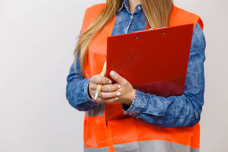 橙色背心的女建筑工人结构程师持有笔文件垫工业作安全室拍摄女程师建筑持有文件垫背景图片