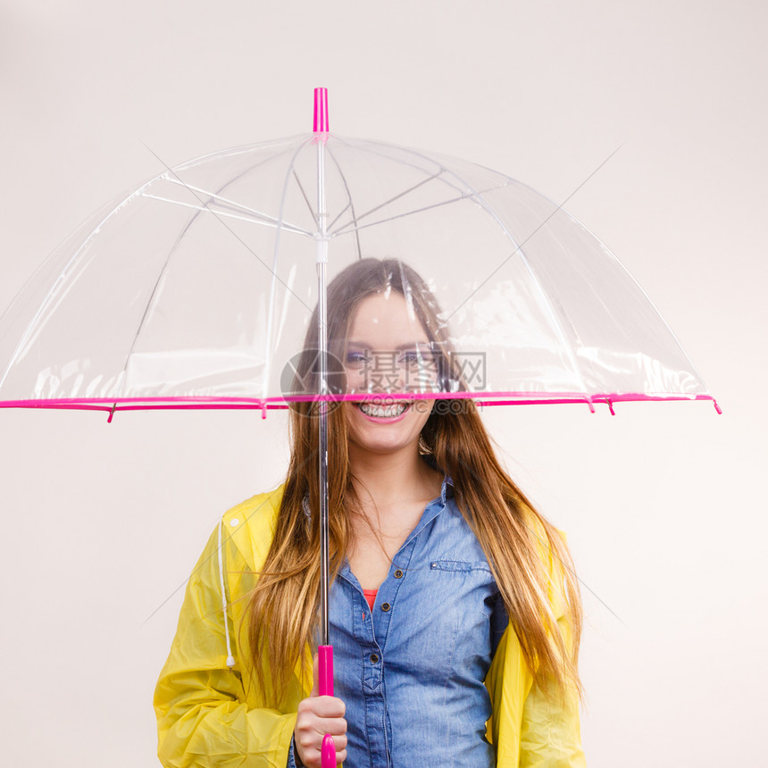 身着防水黄色大衣站在雨伞下玩得开心的雨中微笑女孩气象预报和天季节概念身着雨伞下防水大衣的妇女图片